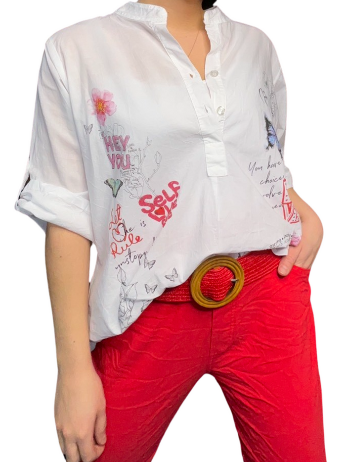 Blouse blanche à manche 3/4 pour femme avec imprimé d'écritures avec ceinture rouge et pantalon rouge.