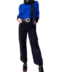 Chandail bleu roi pour femme à manche longue avec ceinture, foulard noir, jeans cargo noir et bottes noires. 