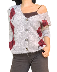 Cardigan en tricot beige à losanges bourgogne porté sur un haut brun, glissé sur l’épaule