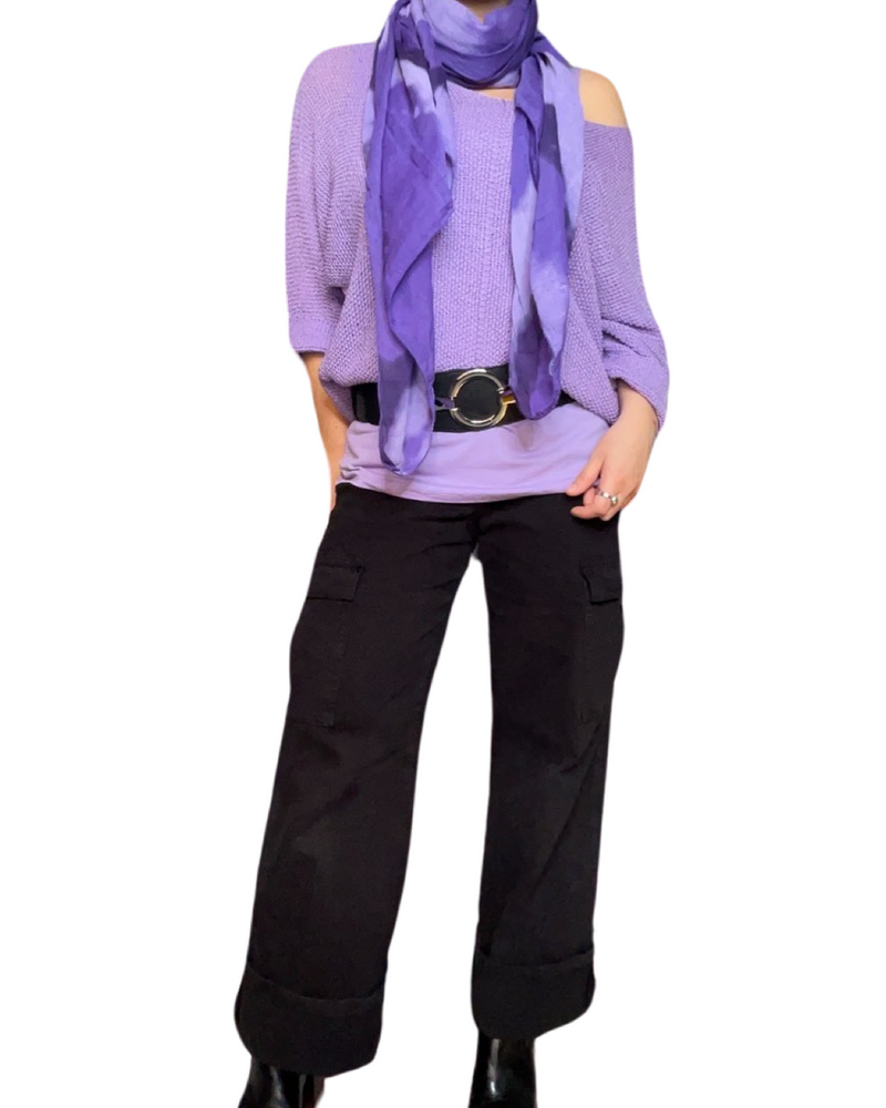 Chandail lilas pour femme à manche longue avec foulard mauve, ceinture, camisole lilas, jeans cargo noir et bottes noires.
