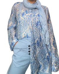 Chemise blanche pour femme imprimé de motifs floraux avec foulard et pantalons bleu ciel.