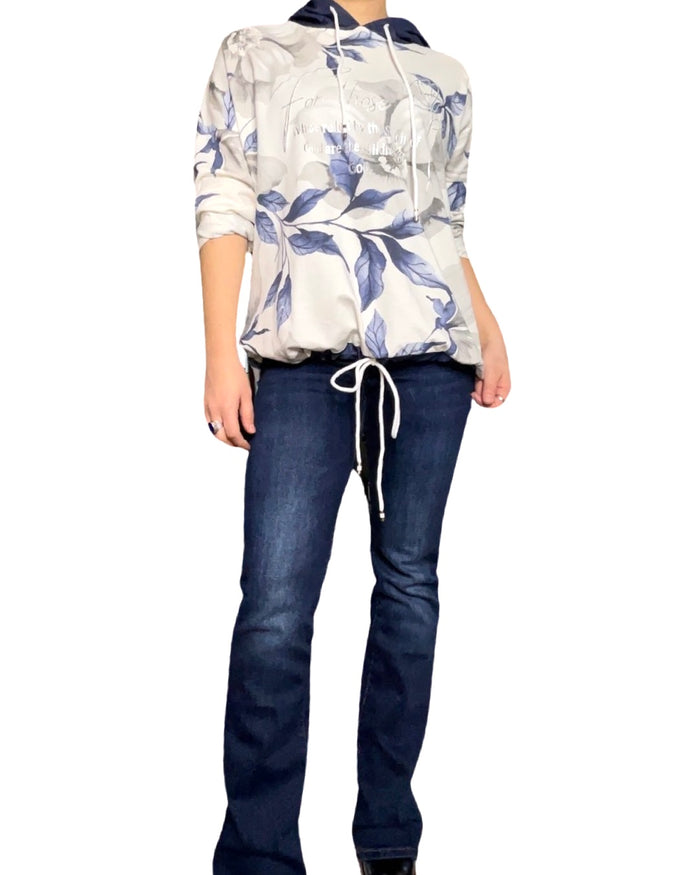 Chandail blanc pour femme manche longue à capuchon avec jeans flare bleu foncé.
