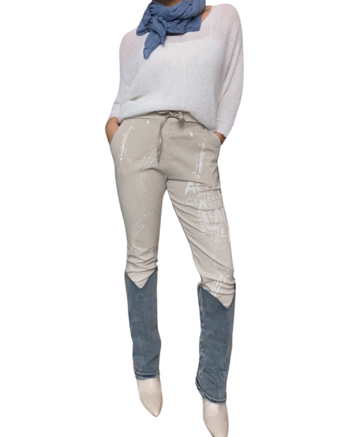 Pantalon beige pour femme à taille élastique avec cordon. Ce kit comporte un foulard, un chandail blanc en maille, une blouse blanche et des bottes beiges avec des accessoires en jeans.