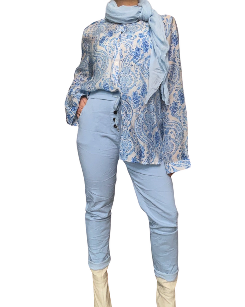 Pantalon bleu pour femme à taille élastique avec 4 boutons avec foulard, chemise et bottes beiges.