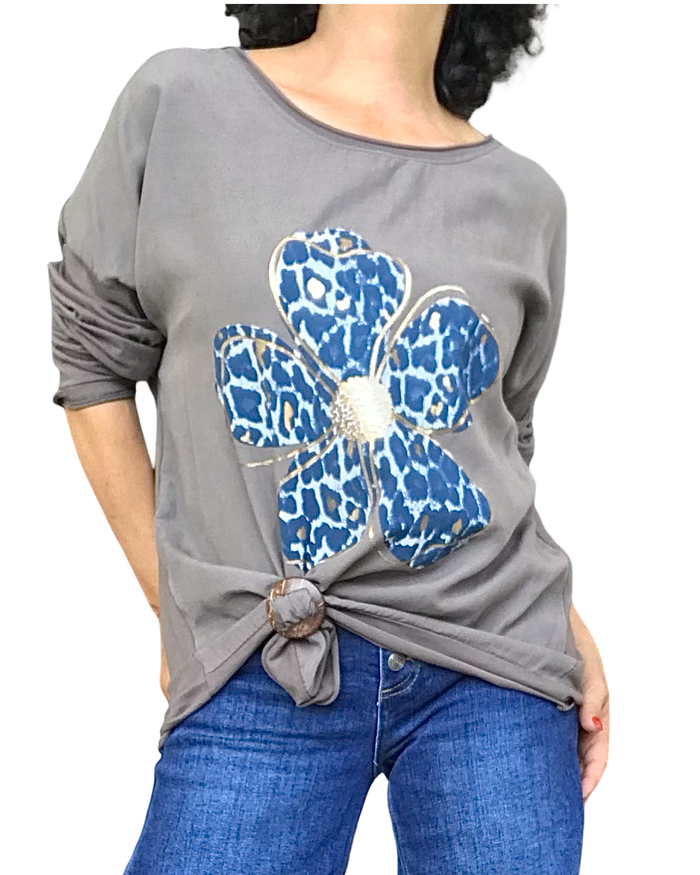 Chandail moka col rond à grande marguerite marine et dorée, noué devant, porté avec jeans bleu