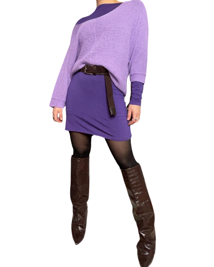 Chandail long mauve uni pour femme à manche longue avec chandail lilas en maille par dessus, ceinture, bas de nylon et bottes brunes longues.