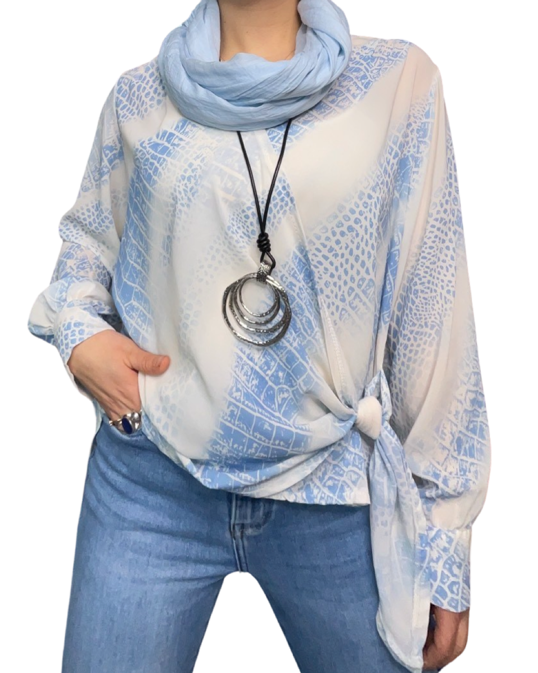Blouse blanche pour femme à manche longue avec noeud et imprimé bleu. Portée avec un foulard et un collier long.