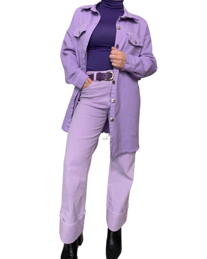 Jacket long en jeans lilas avec col roulé mauve, ceinture mauve, jeans lilas et bottes noires.