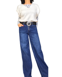 Jeans droit bleu foncé délavé porté avec un pull sans manches crème et une ceinture à boucle argentée