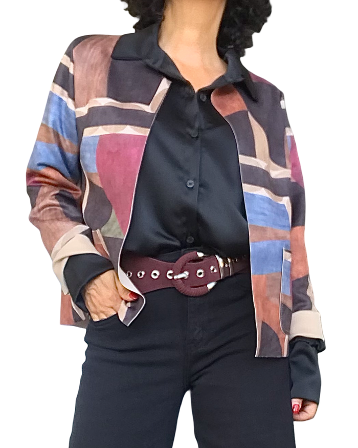 Veston court multicolore en ultrasuède porté ouvert sur une chemise noire en satin, avec ceinture bourgogne