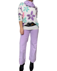 Chandail blanc pour femme manche longue imprimé de fleurs mauve et aqua avec foulard, ceinture, jeans lilas et bottes noires.
