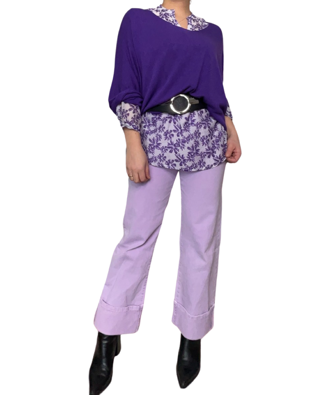 Blouse blanche pour femme imprimé de motifs floraux mauves avec chandail mauve, ceinture noire, pantalons lilas et bottes noires.