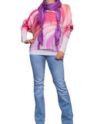 Chandail pour femme avec imprimé abstrait rose et mauve avec foulard, collier long, chandail blanc à l'intérieur et jeans.