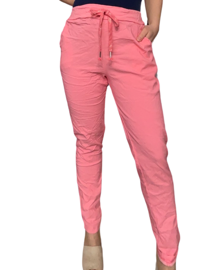 Pantalon corail pour femme à taille élastique avec cordon. Ce kit comporte une camisole bleue marin à l'intérieur du pantalon et des talons hauts beiges.