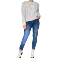 Chandail blanc manche longue pour femme à mailles multicolores, ceinture brune et jeans jambe droite, botte blanche