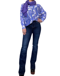 Chandail femme lilas à manche longue avec imprimé de coeurs avec foulard mauve, jeans flare bleu foncé et bottes noires.