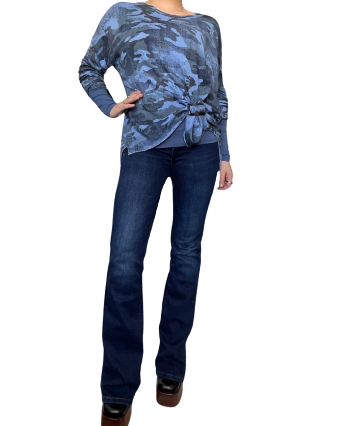 Chandail bleue pour femme à manche longue avec boucle d'ajustement, chandail à manche longue à l'intérieur, jeans flare bleu foncé et bottes noires.