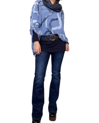 Blouse bleue lilas oversize pour femme à motifs avec chandail à manche longue, foulard, ceinture, jeans flare et bottes noires.