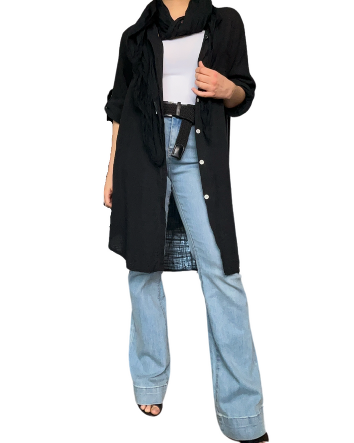 Chemise longue noire à manche 3/4 pour femme avec ceinture noire et jean flare.
