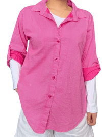 Chemise pour femme à manche longue fuchsia rayée portée over size avec chandail à manche longue et short blanc.