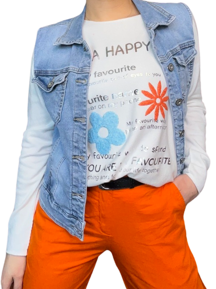 Chandail blanc pour femme avec imprimé d'écritures et de fleurs avec veste en jeans, pantalon orange et ceinture noire.