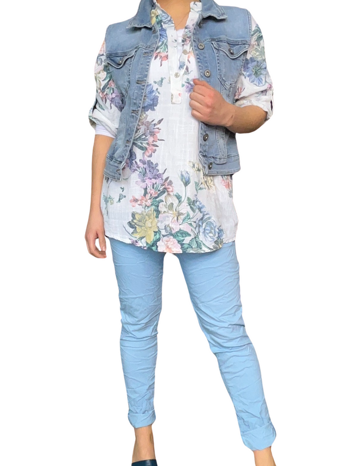 Blouse blanche pour femme avec imprimé florale de couleurs variées avec veste en jeans et pantalon.