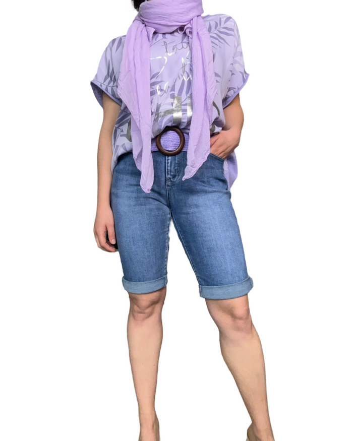 T-shirt lilas pour femme avec imprimé de feuilles avec une ceinture lilas et un bermuda en jean.
