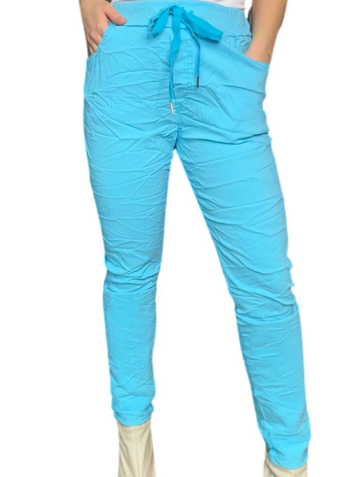 Pantalon turquoise pour femme à taille élastique avec cordon avec camisole gainante à l'intérieur et bottes beige.