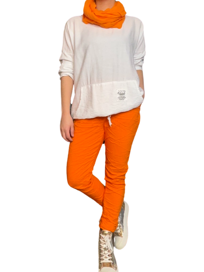 Chandail blanc pour femme à manche longue avec bas ajustable avec pantalon orange et converse.