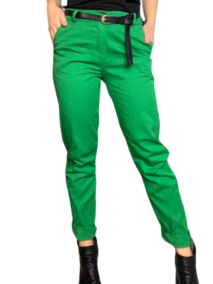 Pantalon cigarette vert pour femme avec ceinture noire avec camisole gainante à l'intérieur et bottes noires.