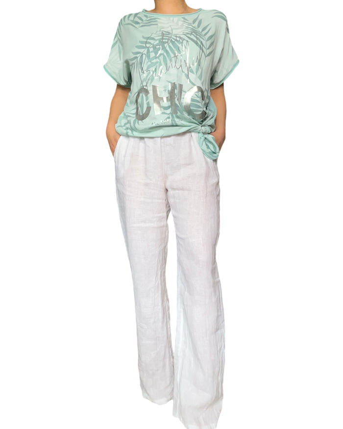 T-shirt vert aqua pour femme avec imprimé de feuilles avec pantalon blanc en lin.