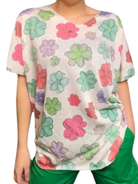 T-shirt blanc pour femme avec imprimé de fleurs multicolores portée over size avec pantalon vert.