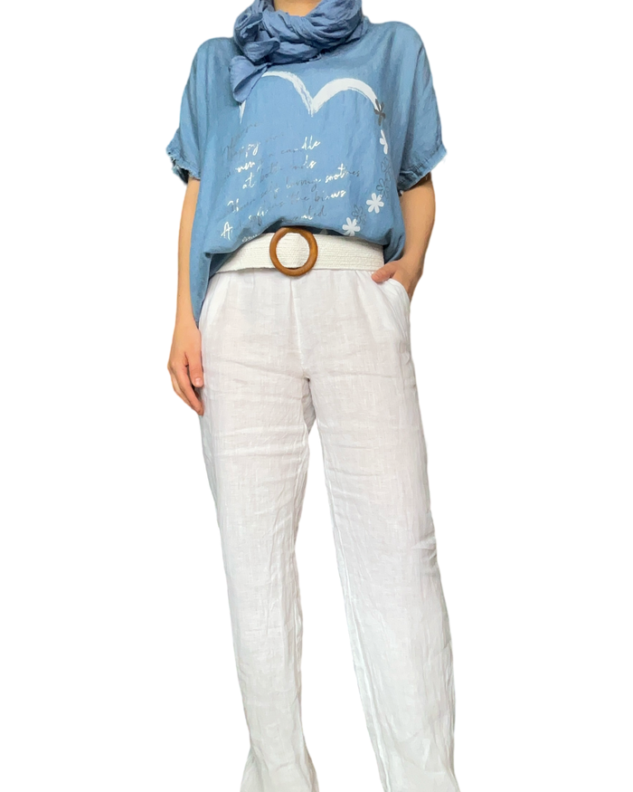 T-shirt bleu jean pour femme avec imprimé d'un cœur avec ceinture blanche en jute et pantalon blanc en lin.
