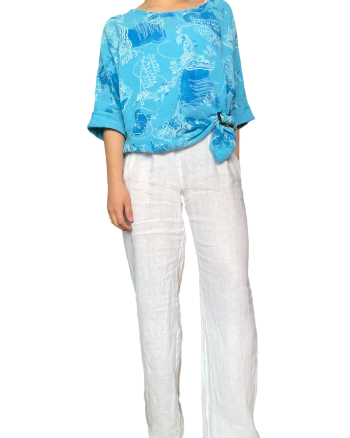 Chandail turquoise pour femme avec imprimé d'écritures avec pantalon blanc en lin.