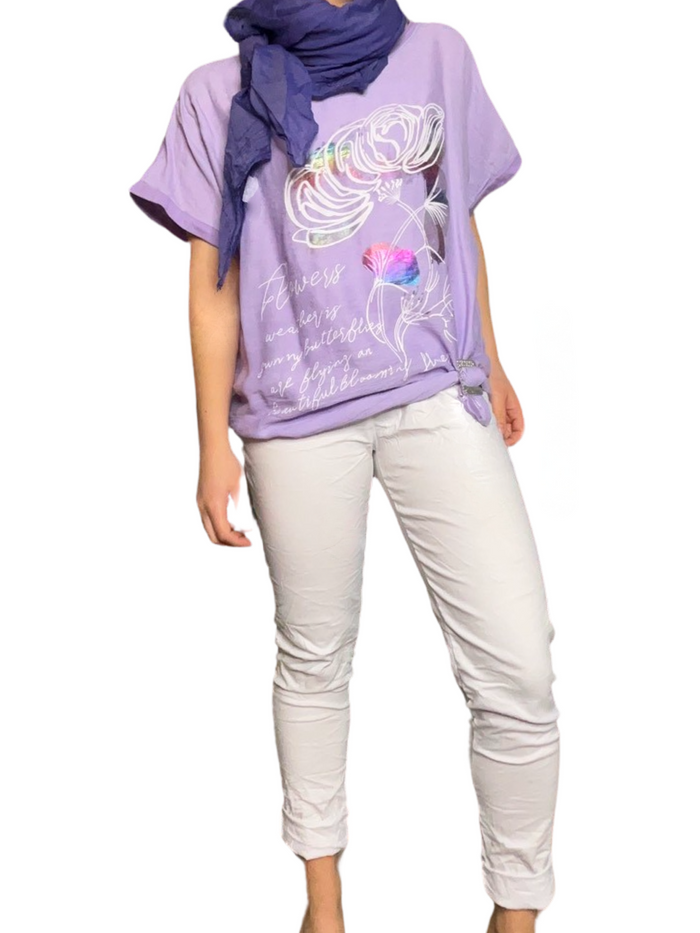 T-shirt lilas pour femme avec imprimé d'une grande fleur avec foulard mauve, boucle d'ajustement et pantalon blanc.
