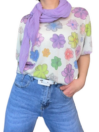 T-shirt blanc pour femme avec imprimé de fleurs multicolores avec foulard lilas, jeans et ceinture blanche.