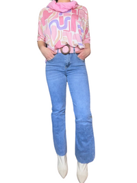Jeans pour femme flare bleu clair 28 pouces de longueur avec chandail rose, foulard rose et ceinture rose.