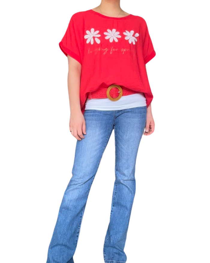 T-shirt rouge pour femme avec imprimé de trois fleurs blanches avec camisole gainante à l'intérieur, ceinture rouge et jean flare.